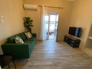 a living room with a green couch and a television at Batis Breeze Suites in (( Filaréton ))