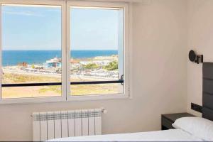 a bedroom with a window with a view of the beach at Argus San Lorenzo By Silastur in Gijón