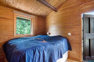 Ce lit se trouve dans une cabane en bois dotée d'une fenêtre. dans l'établissement Classic Danish Summerhouse Experience 250m From The Sea, à Liseleje