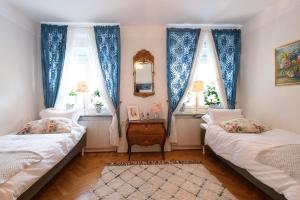 a bedroom with two beds and two windows at HoMade B&B, Gamla Stan in Norrköping
