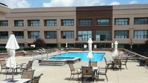 a pool in front of a building with chairs and umbrellas at Condo with Lake & Cedar Point Views From Balcony. in Sandusky