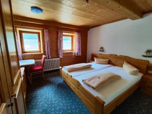 um quarto com 2 camas, uma mesa e uma cadeira em Gasthaus Mitterjager em Kirchdorf in Tirol