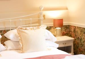 a bedroom with a white bed with a pillow on it at Fleur de Lys Bampton in Bampton