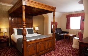 um quarto de hotel com uma cama e uma cadeira em Fieldhead Hotel by Greene King Inns em Markfield