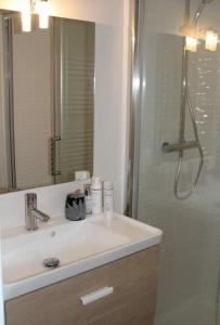 a bathroom with a sink and a shower with a mirror at Zenitude Place in Margny-lès-Compiègne