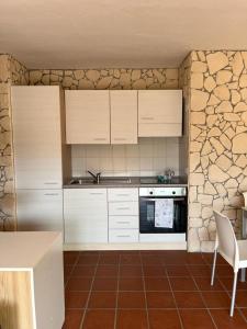 cocina con armarios blancos y pared de piedra en Domus Petra Porto Rotondo, en Porto Rotondo