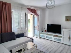 uma sala de estar com um sofá e uma televisão de ecrã plano em Apartmani Rameša em Murter
