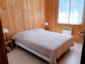 una camera con un letto su una parete in legno di maison avec piscine a Le Porge