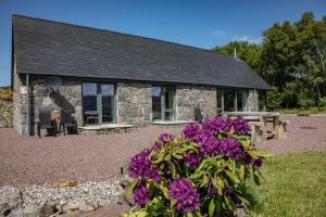 a stone cottage with purple flowers in front of it at Avernish Lodge-Luxury Self Catering in Kirkton