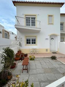 een wit huis met een bankje ervoor bij Wave - Beach House, Baleal in Baleal