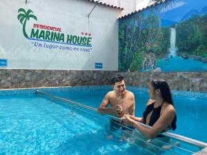 un homme et une femme assis dans une piscine dans l'établissement Residencial Marina House, à Tarapoto