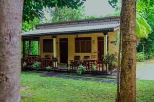 a yellow house with tables and chairs in a yard at Sigiri Nirwana Lodge in Sigiriya