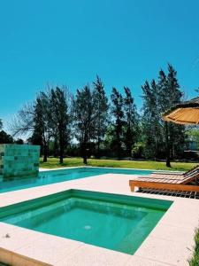 a swimming pool with a table and an umbrella at Quinta Las Flores in Reconquista