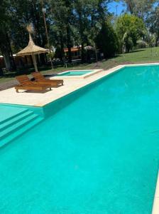 a swimming pool with two benches and an umbrella at Quinta Las Flores in Reconquista