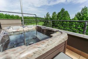 a hot tub on a balcony with trees at Lotus Therme Hotel & Spa in Hévíz