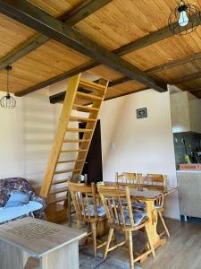 a dining room with a wooden staircase and a table and chairs at Vikendica Jagoš in Mitrovac