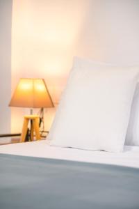 um close-up de uma cama branca com um abajur em Ktima Petrina Volia- Maisonette Phos em Andros