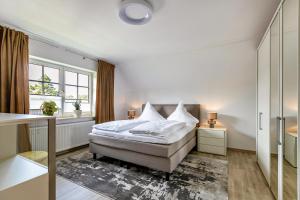 a white bedroom with a bed and a window at Ferienwohnung Meeressand in Sankt Peter-Ording