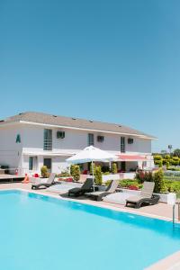 a pool with chairs and umbrellas next to a building at Vela Garden Resort in Alaçatı