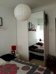 Dormitorio con espejo, cama y lámpara en Casa da catarina en Linda-a-Velha