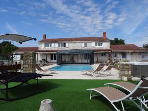 a house with a yard with chairs and a swimming pool at les gîtes de La Cossais in Saint-Cyr-en-Talmondais
