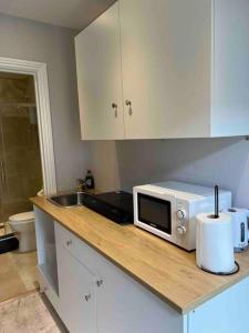 a kitchen counter with a microwave and a sink at Newly built Large garden ensuite guest studio in Borehamwood