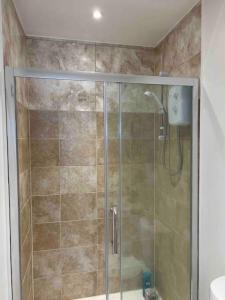 a shower with a glass door in a bathroom at Newly built Large garden ensuite guest studio in Borehamwood