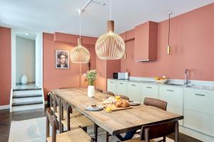 een keuken met een houten tafel en stoelen en roze muren bij Stylish Spacious Flat w 3BR in Copenhagen City in Kopenhagen