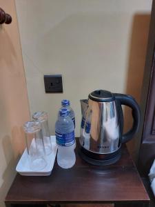 Edwin's Airport Garden في نيجومبو: وجود صانعة قهوة وزجاجات ماء على طاولة
