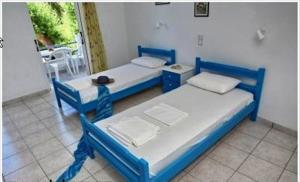 two blue beds in a room with a balcony at Pano sto Kyma Studios in Plomari