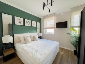um quarto com uma cama branca e uma parede verde em My Baltic Sea - Ferienwohnungen im Saltwater House em Scharbeutz