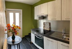 een keuken met een vaas met bloemen op een tafel bij Le Clos de la Belle Loge Location de studio in Frasnoy