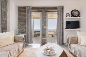 a living room with a couch and a table and a tv at Ktima Petrina Volia- Maisonette Phos in Andros