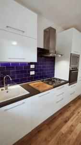 a kitchen with white cabinets and a sink and blue tiles at MareBlu Appartamento in Marina di Castagneto Carducci