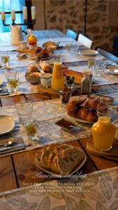 una larga mesa de madera con comida. en Maison Dix Chambres d'hôtes en Néffiès