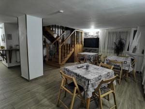 a dining room with tables and chairs and a staircase at Craita in Căpăţîneni-Ungureni