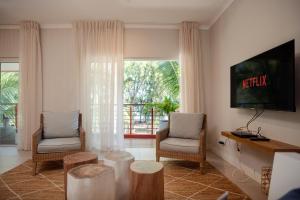 Una sala de estar con dos sillas y un televisor. en Blue Coral Beachfront Penthouse, en Flic en Flac