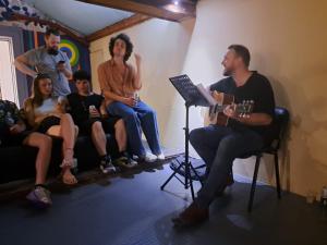 Bla Bla Hostel في صوفيا: مجموعة من الناس يجلسون في غرفة مع عازف غيتار
