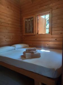 een bed in een houten kamer met twee handdoeken erop bij ECOLODGE CABAÑEROS 