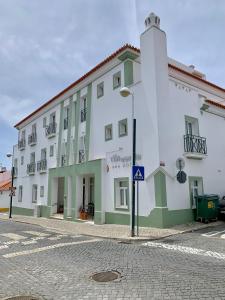 a white building with green trim on a street at Hotel Vila Verde in Castro Verde