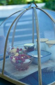 una jaula con cuencos de fruta sobre una mesa en LE MOULIN DE LONGCHAMP - Maison d'Hôtes, en Lent