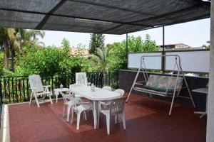a patio with a table and chairs and a swing at Blue Coast Sicily in Fondachello