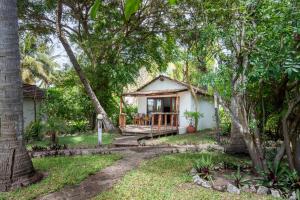 a cottage in the woods with a porch and trees at LEMON BEACH LODGE Vilankulo in Vilanculos