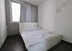 Schlafzimmer mit einem Bett mit weißer Bettwäsche und einem Fenster in der Unterkunft TEL AVIV - Front of the sea in Tel Aviv