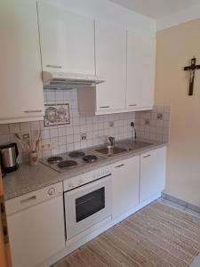 una cocina con armarios blancos y fregadero en Apart Onkl, en Sankt Leonhard im Pitztal