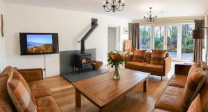 een woonkamer met een tafel en een open haard bij Sawmill Cottage, Coniston Water in Coniston