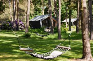a hammock in a park with a cabin in the background at KampinaStaete Diamond Suite in Oisterwijk