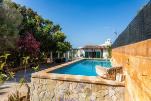 a swimming pool with a retaining wall and a stone wall at Sa Casa des Pintor Miquel Vives 213 in Cala Bona