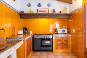 uma cozinha com uma parede de azulejos laranja em Sa Casa des Pintor Miquel Vives 213 em Cala Bona