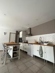 a kitchen with white cabinets and a table in it at Villa piscine confort cosy in Brouilla